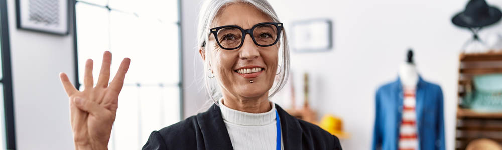 Older woman in a suit holding up four fingers Older woman in a suit holding up four fingers